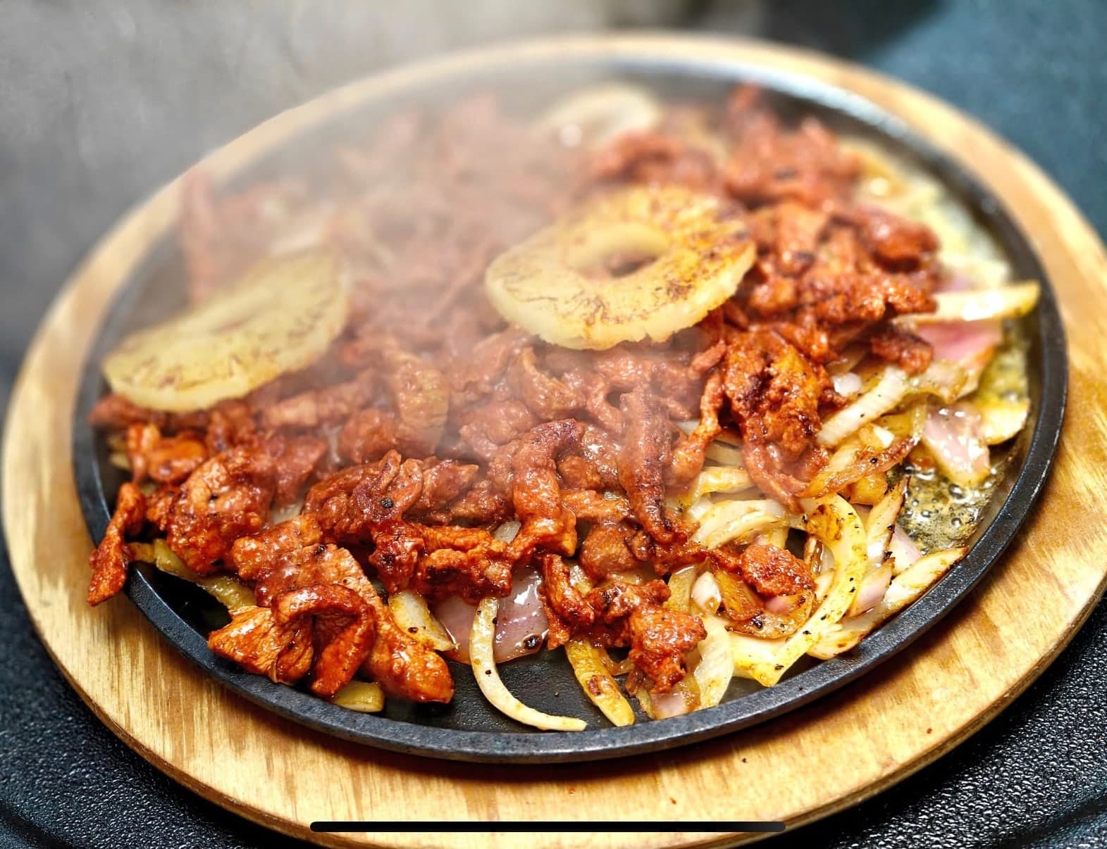 Sizzling fajitas with grilled meat, peppers and onions.