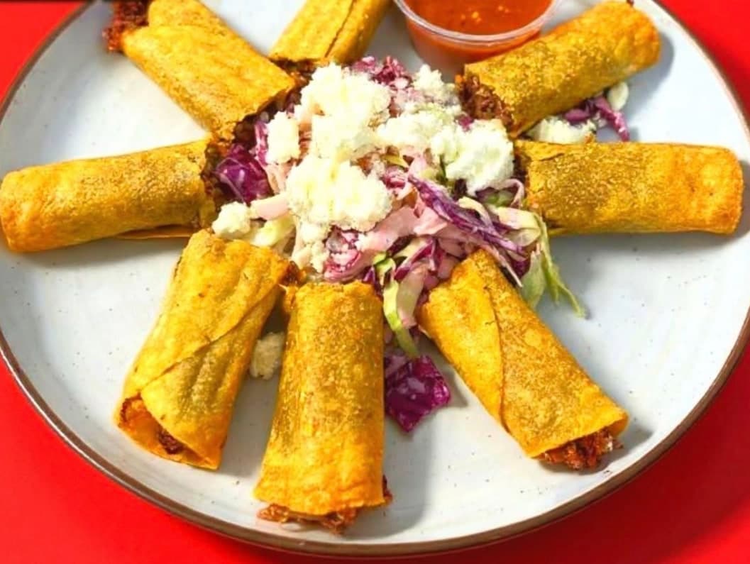 A plate of crispy flautas with crema and cotija.